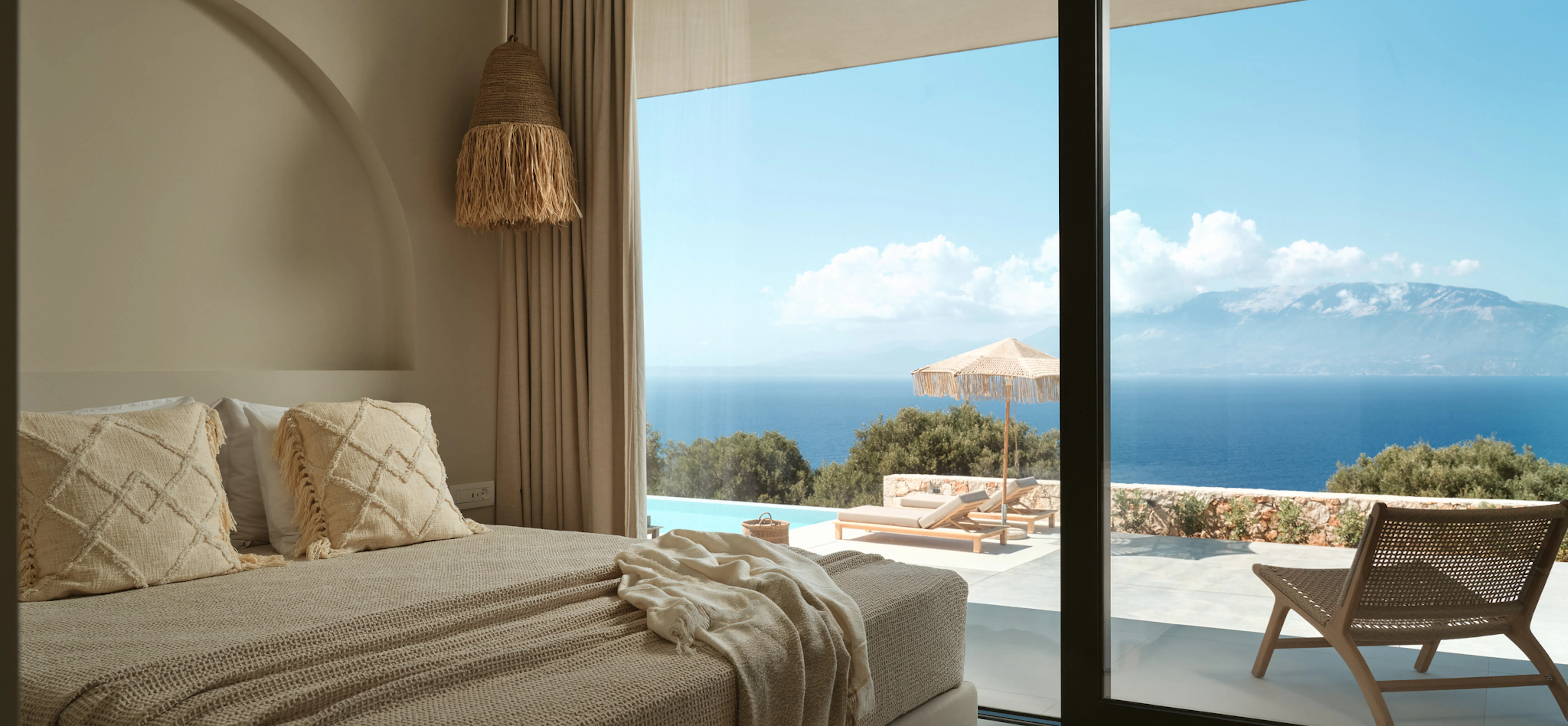 Bedroom with diamond-textured throw pillows, sliding glass doors opening onto a private pool terrace and sea view.