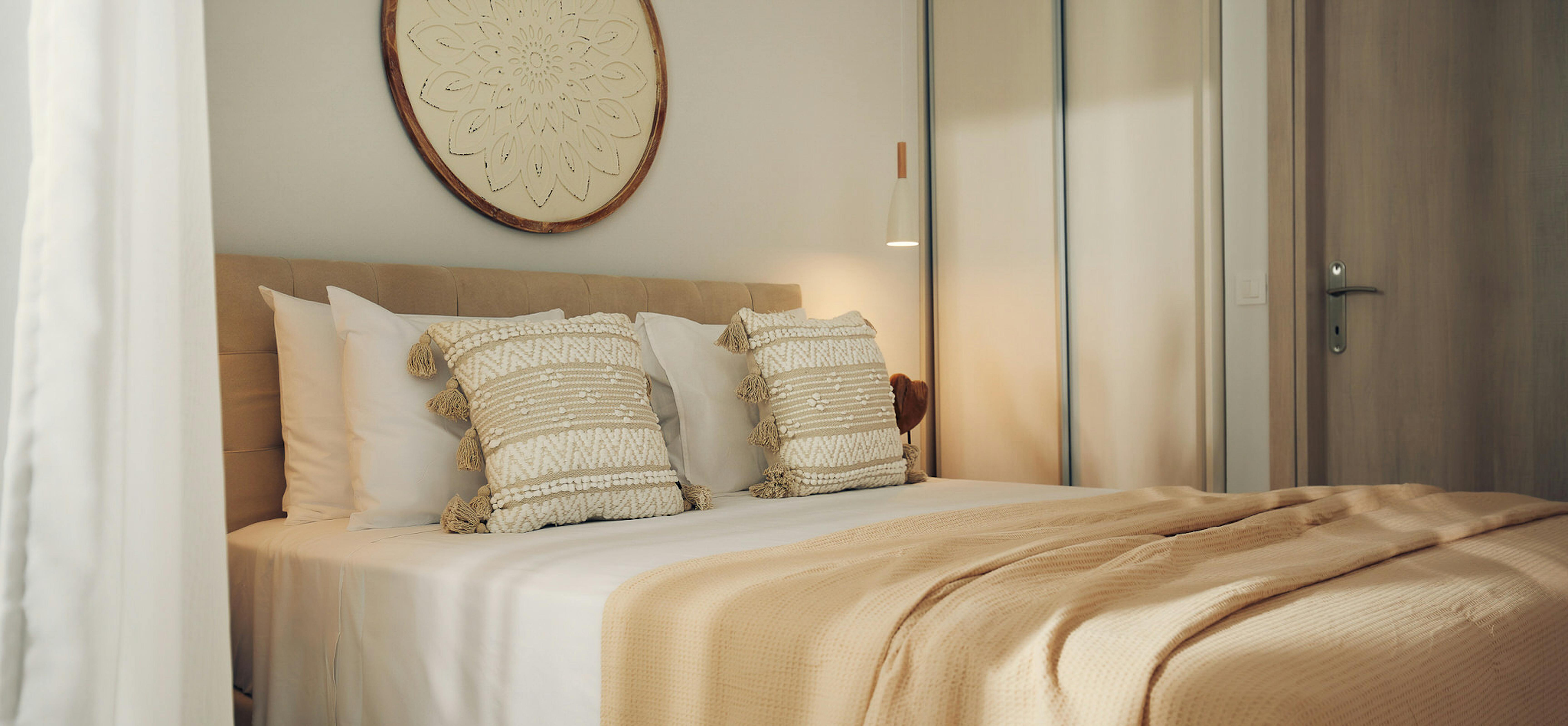 Bedroom at dusk with ocean-view terrace, loungers visible through open doors, and decorative wall medallion.