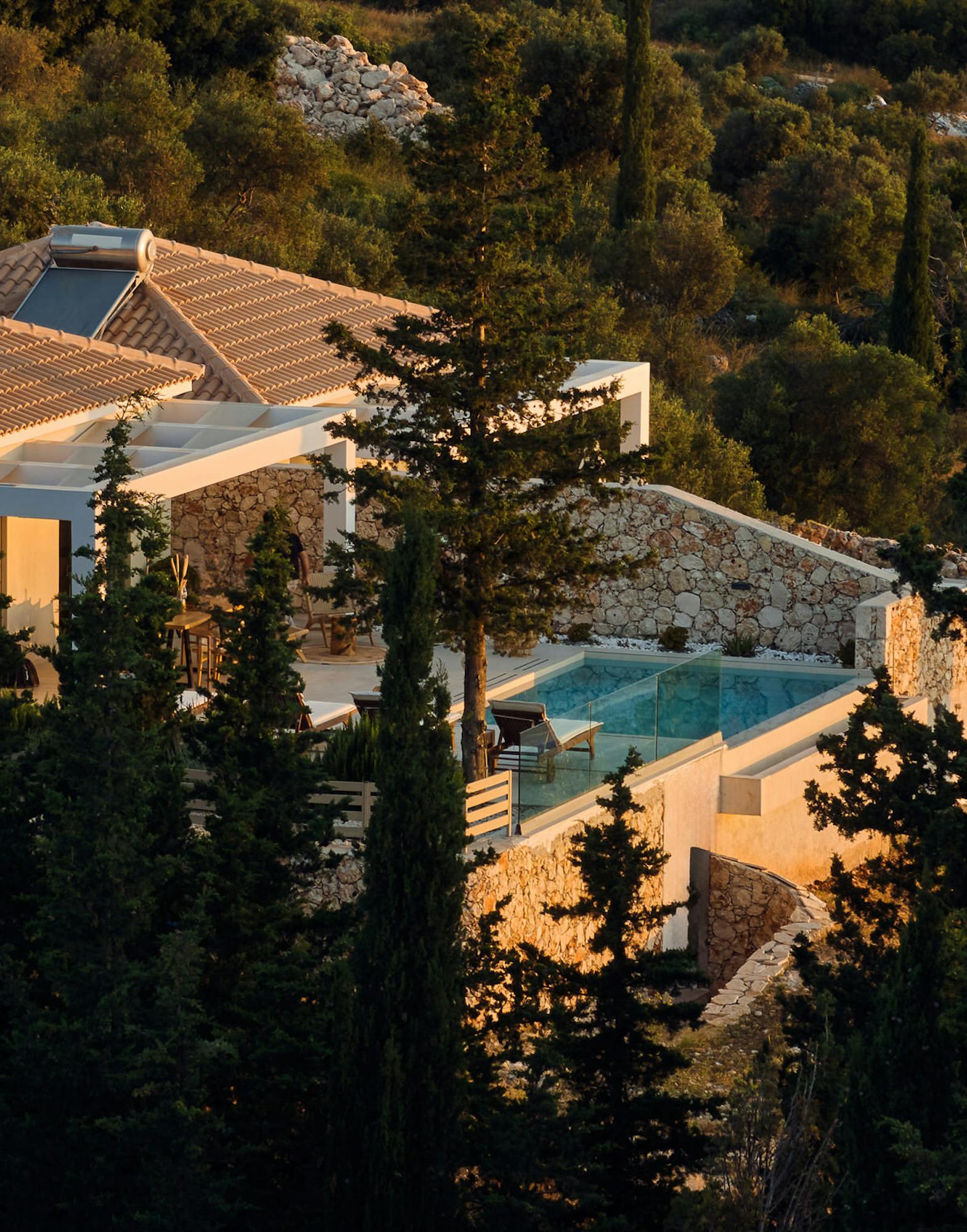Minimalist bedroom corner with upholstered bed, tasseled pillows, pendant lights, and mirror wardrobe reflecting soft light.