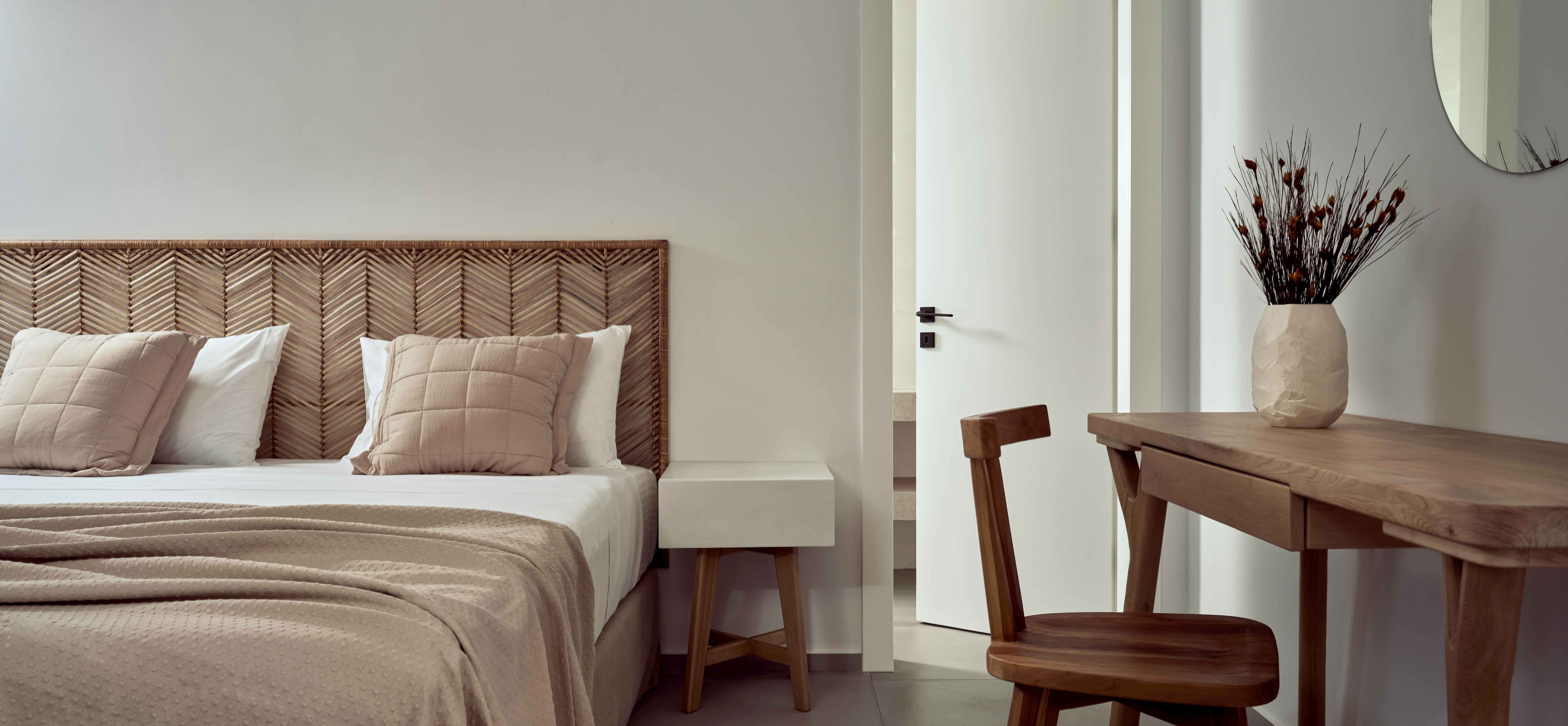 Modern bedroom with geometric wooden headboard, neutral textiles, and work desk by window.