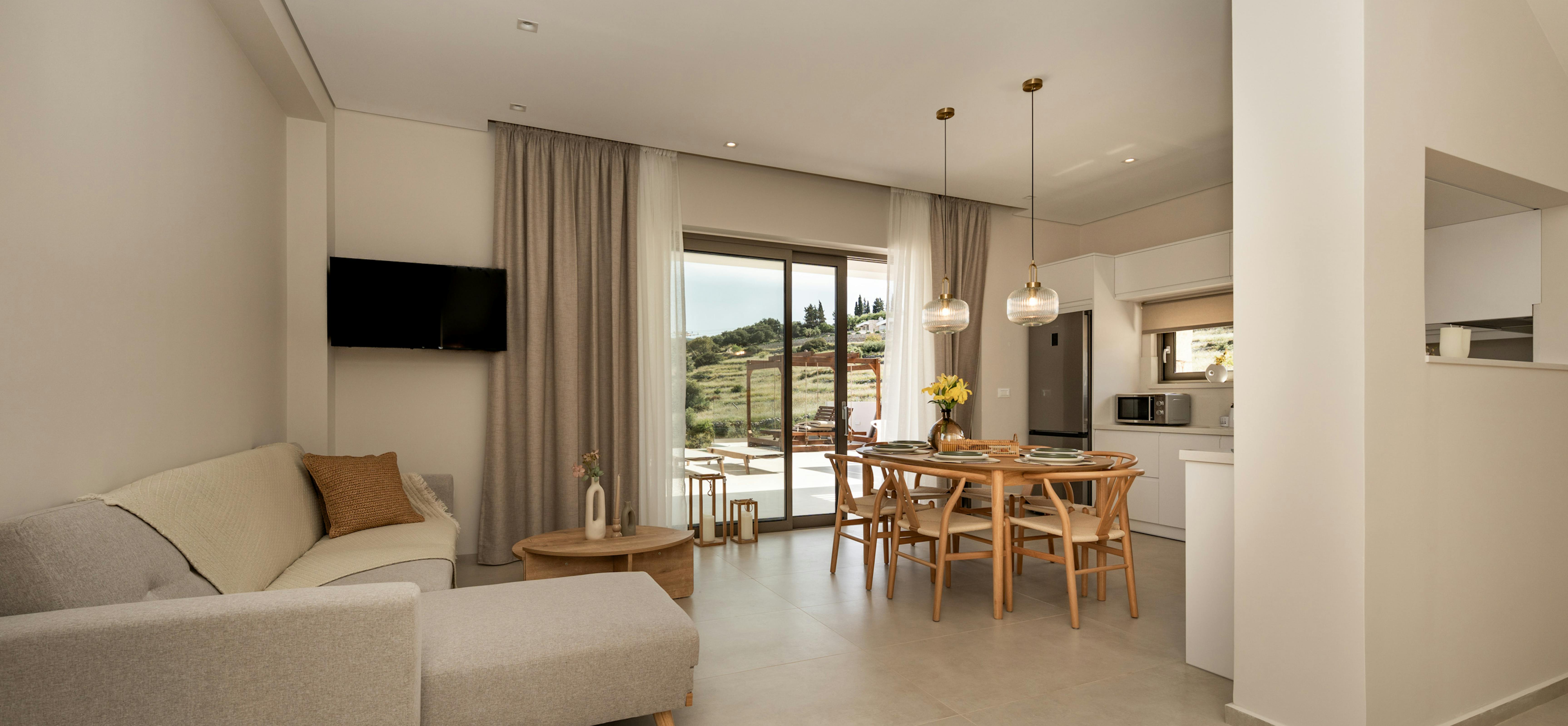 Contemporary living space with gray sectional sofa, dining area, and glass doors to outdoor terrace.