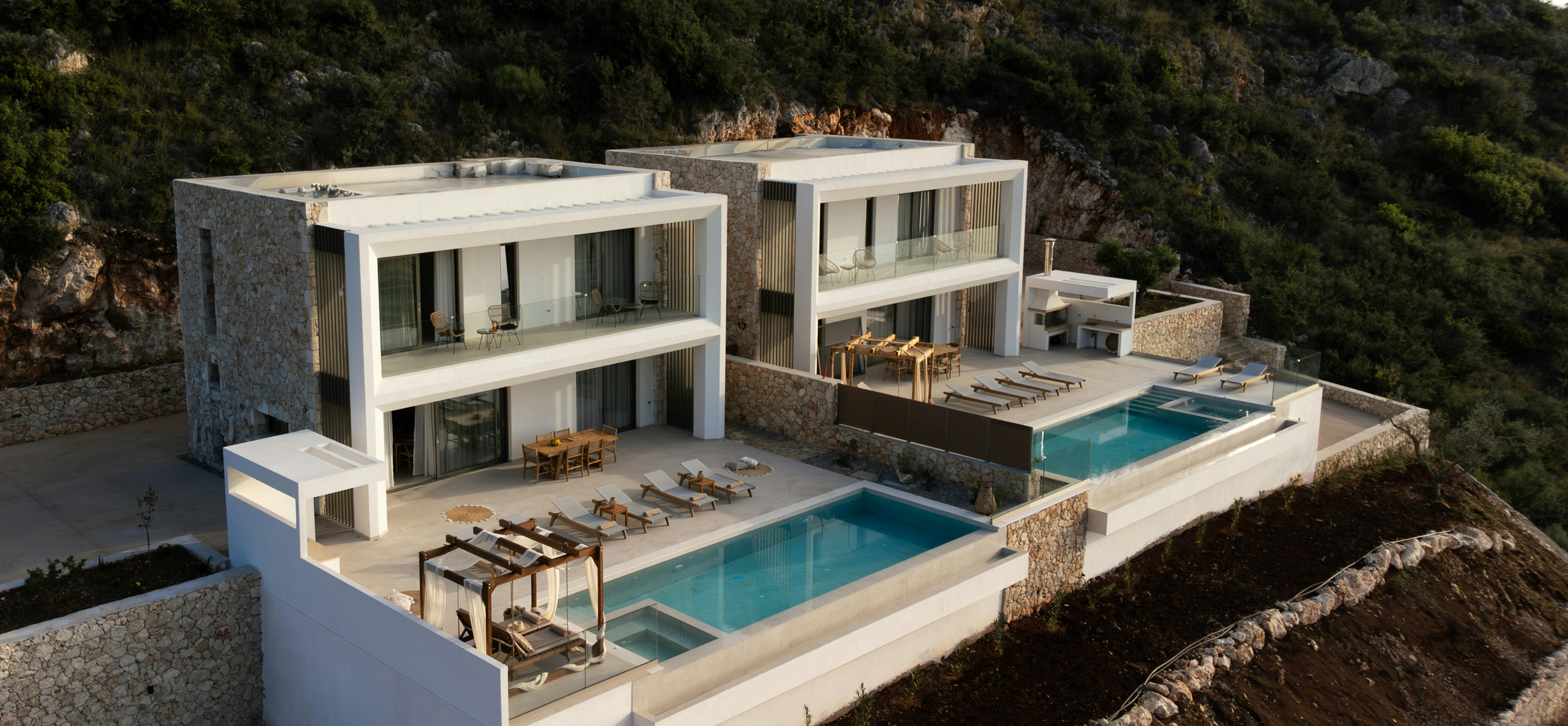 Â Expansive modern villa complex with multiple pools and terraces carved into hillside.