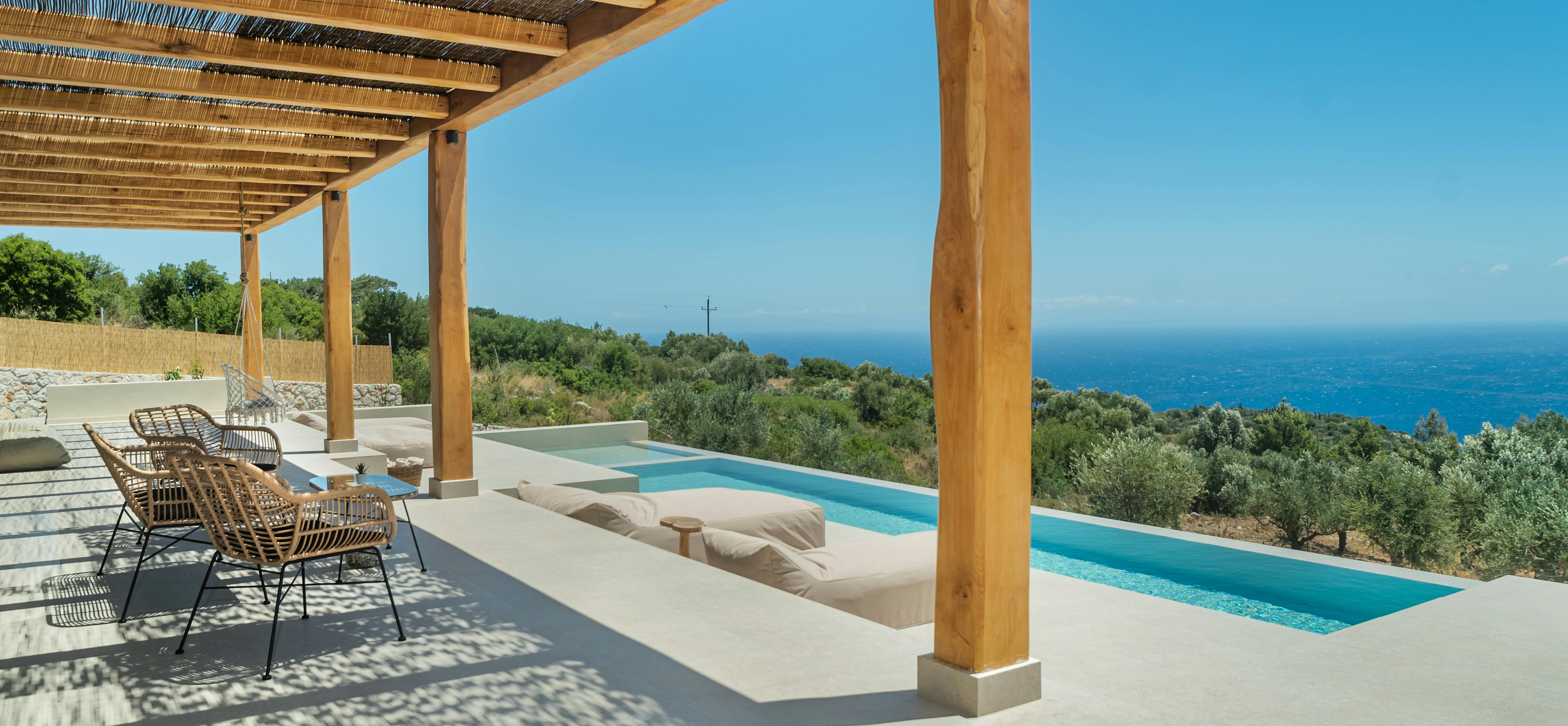 Shaded pergola terrace with sunken seating area beside tiered infinity pool and sea views.