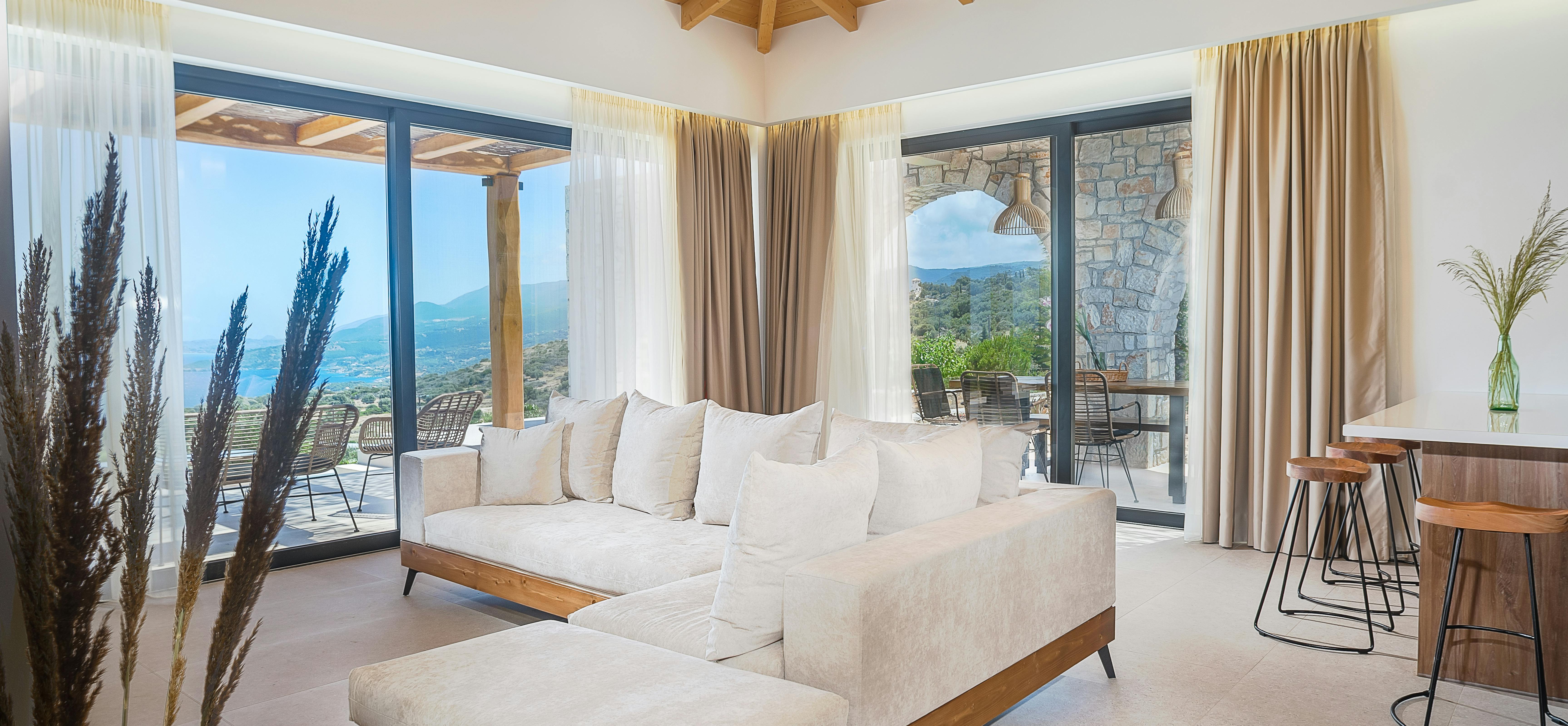 Living room with beige sectional sofa, vaulted wood ceiling, and panoramic terrace views.