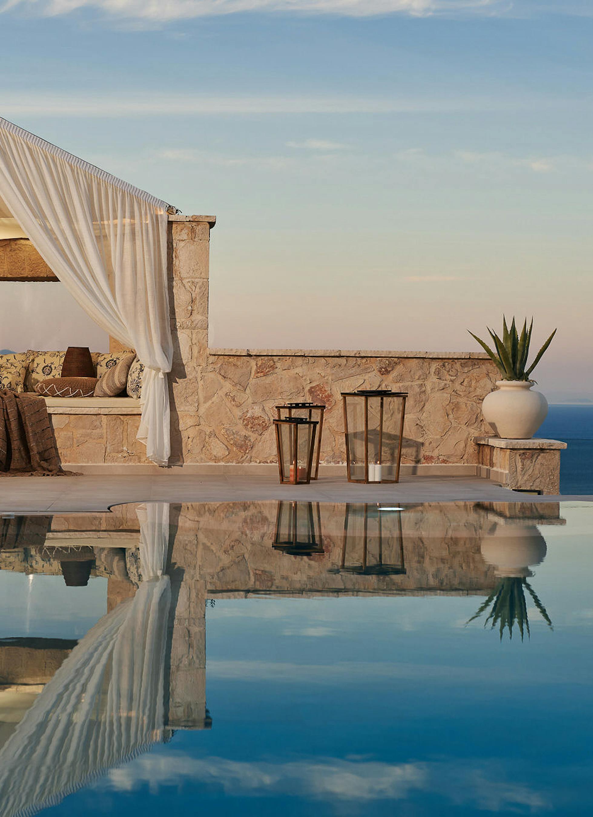 Evening infinity pool scene with stone cabana and perfect reflections of sky and architecture.